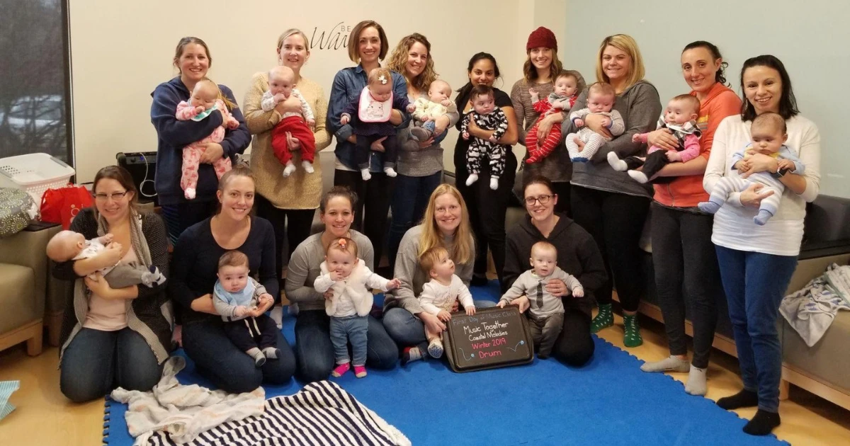A group of moms holding their babies, posing together after group