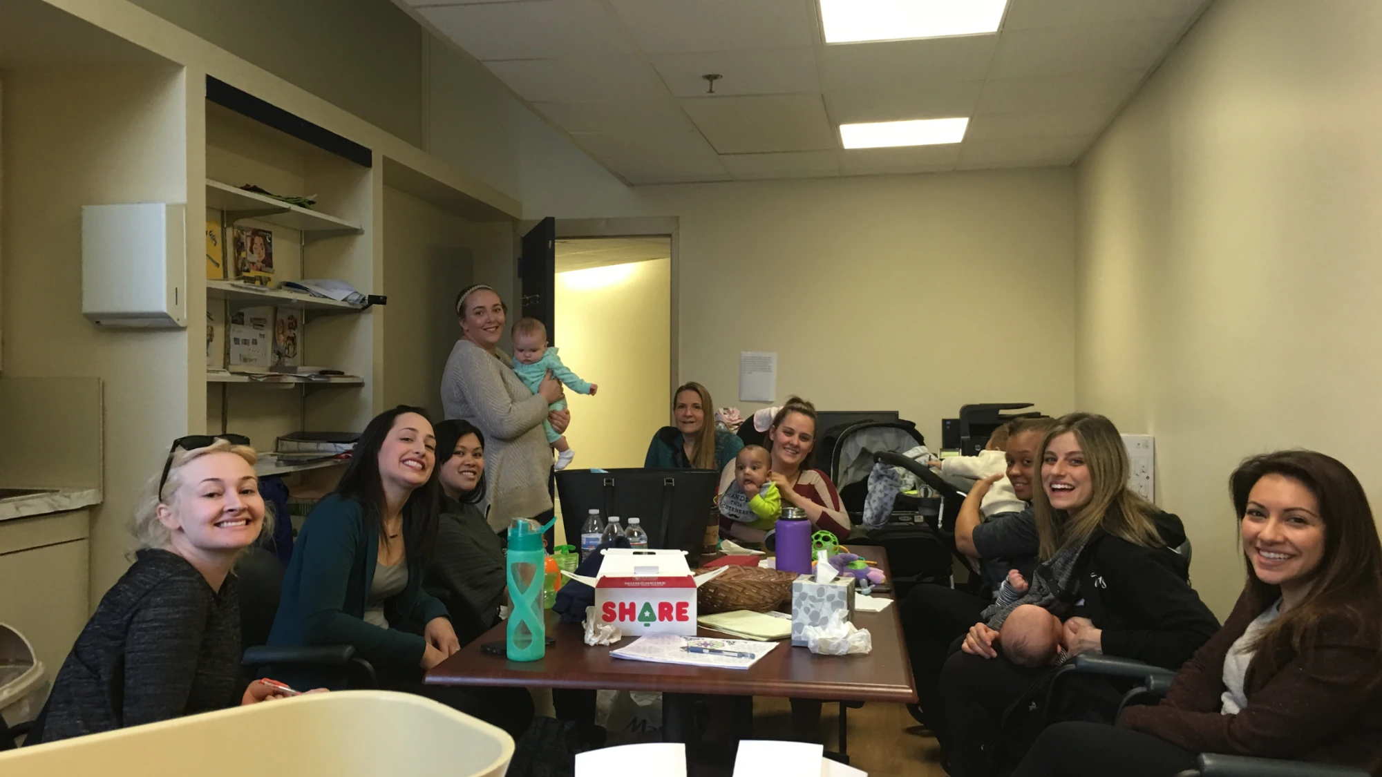 Moms and babies smiling around a table during a support group