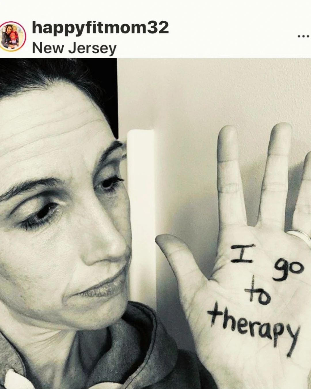 A mom holds up her palm with the words I go to therapy written on it